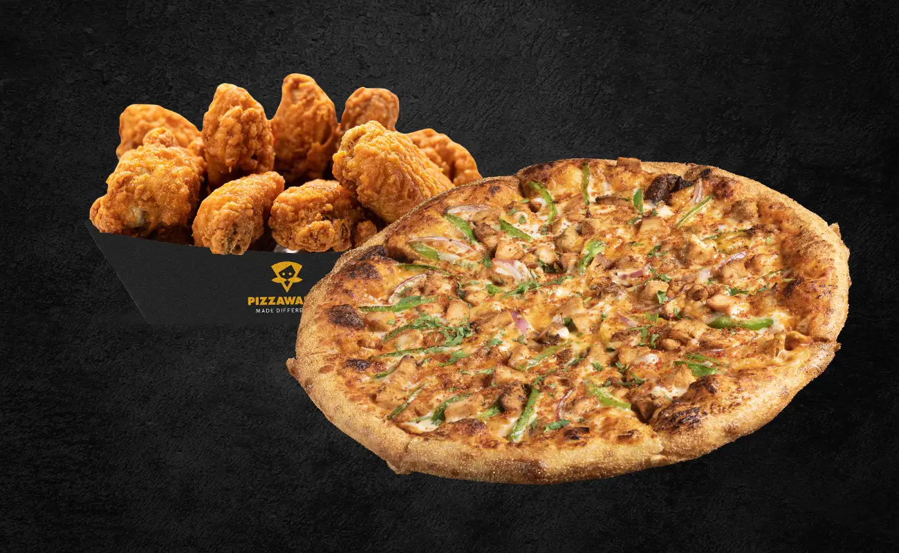 Crispy fried chicken wings served in a branded box alongside a large Indian-style pizza topped with paneer, onions, and green peppers on a dark background.
