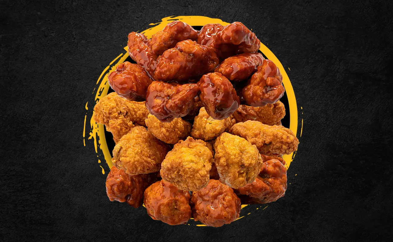 Plate of assorted crispy BBQ wings with a mix of buffalo and naked fried varieties on a dark background