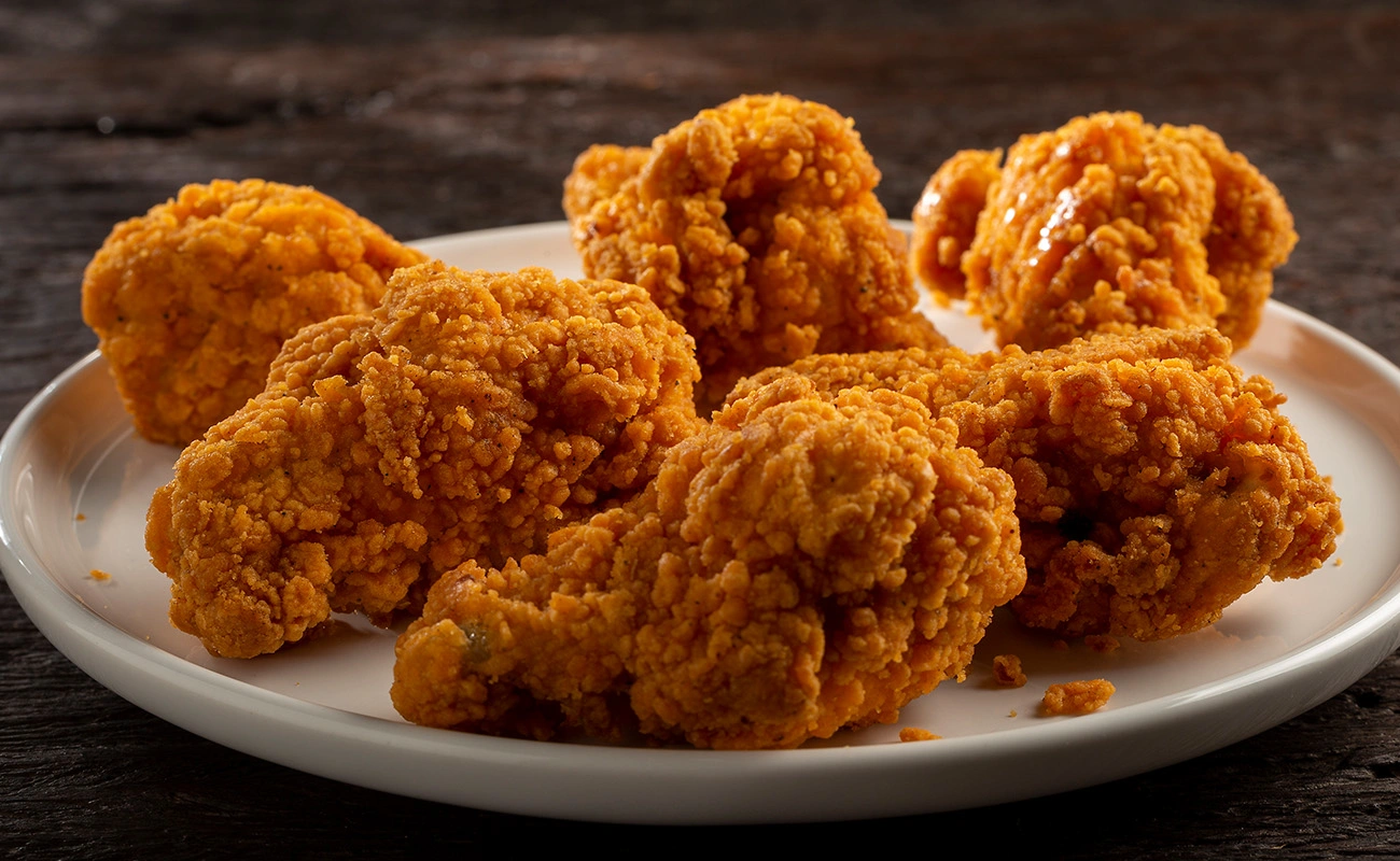 Golden crispy fried chicken wings served on a white plate – crunchy and flavorful appetizer